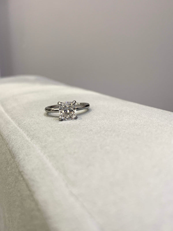 Cushion-Cut Center Stone with Diamond Hidden Halo Engagement Setting  This ring features a square cushion brilliant center stone set in an all-around comfort fit rounded solitaire shank with a diamond basket that elegantly cradles the center stone.