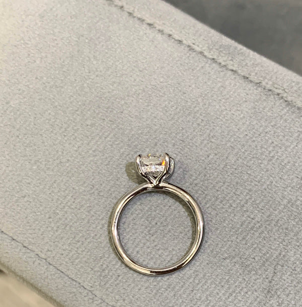 Cushion-Cut Center Stone with Diamond Hidden Halo Engagement Setting  This ring features a square cushion brilliant center stone set in an all-around comfort fit rounded solitaire shank with a diamond basket that elegantly cradles the center stone.